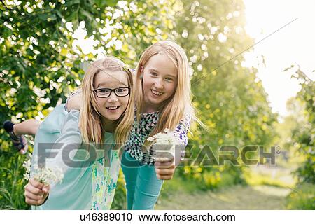 Portrait of two sisters leaning forward with bunches of wildflowers View Large Photo Image Stock Image - Portrait of two sisters leaning forward with bunches of wildflowers. Fotosearch