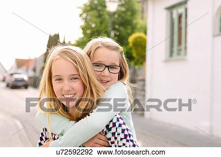 Portrait of two sisters playing piggyback View Large Photo Image Stock Image - Portrait of two sisters playing piggyback. Fotosearch