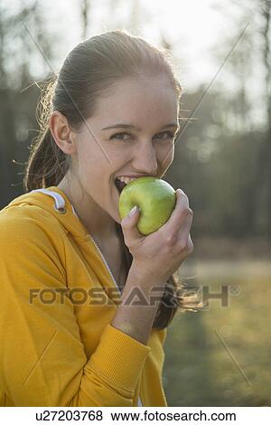 Portrait of young female runner eating an apple View Large Photo Image Stock Photo - Portrait of young female runner eating an apple. Fotosearch