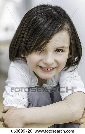 Portrait of young girl hugging knees, smiling View Large Photo Image Stock Image - Portrait of young girl hugging knees, smiling. Fotosearch