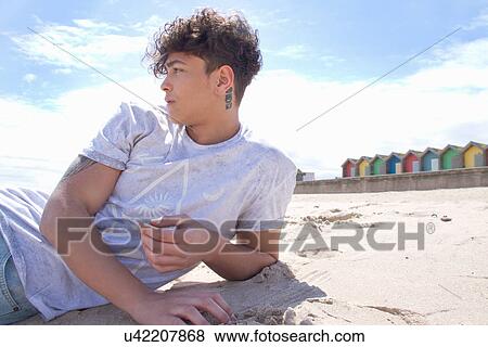 Portrait of young man lying on beach View Large Photo Image Stock Photo - Portrait of young man lying on beach. Fotosearch