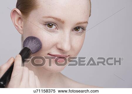 Portrait of young woman, applying make up View Large Photo Image Stock Photography - Portrait of young woman, applying make up. Fotosearch