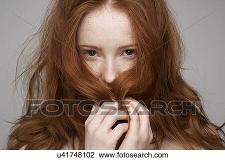 Stock Image - Portrait of young woman, hands in hair. Fotosearch