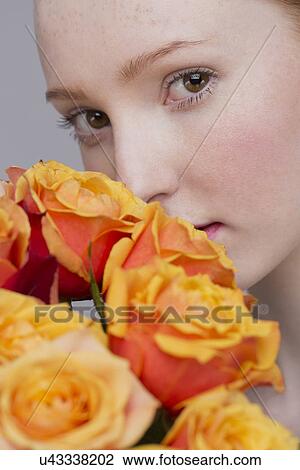 Stock Image - Portrait of young woman, holding bunch of roses. Fotosearch