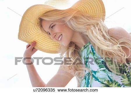 Portrait of young woman holding onto sunhat View Large Photo Image Stock Photography - Portrait of young woman holding onto sunhat. Fotosearch