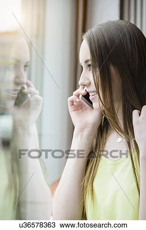 Portrait of young woman in cafe using smartphone and looking out of window View Large Photo Image Stock Image - Portrait of young woman in cafe using smartphone and looking out of window. Fotosearch