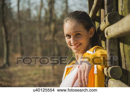 Portrait of young woman leaning against fence in forest View Large Photo Image Picture - Portrait of young woman leaning against fence in forest. Fotosearch