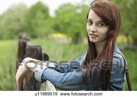 Portrait of young woman leaning on rustic fence View Large Photo Image Stock Photo - Portrait of young woman leaning on rustic fence. Fotosearch