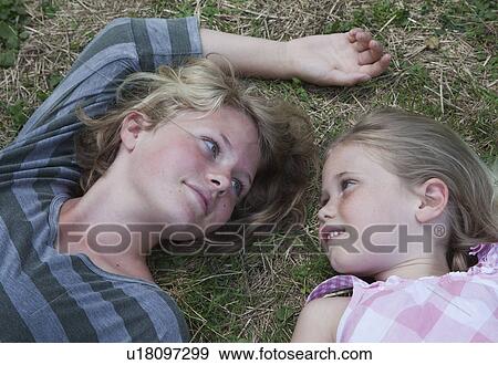 Sisters lying on grass, face to face View Large Photo Image Stock Photo - Sisters lying on grass, face to face. Fotosearch