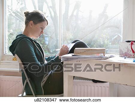 Sixteen year old girl studying and writing notes next to window View Large Photo Image Stock Photo - Sixteen year old girl studying and writing notes next to window. Fotosearch