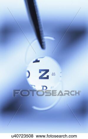 Stock Photo - Snellen eye chart seen through an intraocular lens. Intraocular lens is artificial and surgically implanted in the human eye following extraction of the natural crystalline lens clouded by cataract.. Fotosearch