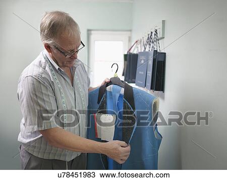 Stock Image - Tailor inspecting clothing in tailoring factory. Fotosearch