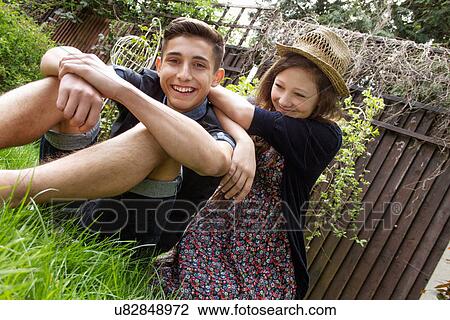 Stock Image - Teenage couple relaxing in garden. Fotosearch