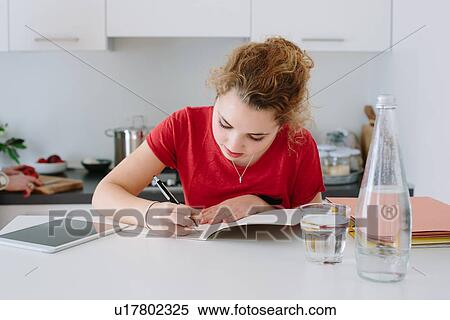 Teenage girl doing homework in kitchen View Large Photo Image Stock Photography - Teenage girl doing homework in kitchen. Fotosearch