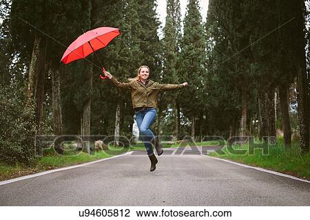 Teenage girl jumping mid air on rural road with umbrella View Large Photo Image Stock Image - Teenage girl jumping mid air on rural road with umbrella. Fotosearch