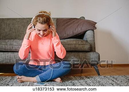 Teenage girl listening to music on headphones in sitting room View Large Photo Image Stock Image - Teenage girl listening to music on headphones in sitting room. Fotosearch