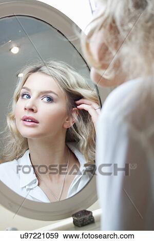 Teenage girl looking in mirror, doing her hair View Large Photo Image Stock Photo - Teenage girl looking in mirror, doing her hair. Fotosearch