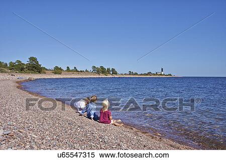 Stock Photography - Three children sitting on beach. Fotosearch