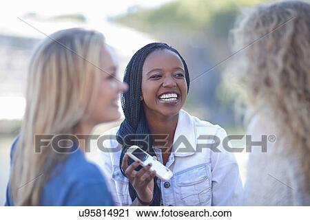 Three young female friends with smartphone laughing View Large Photo Image Stock Image - Three young female friends with smartphone laughing. Fotosearch