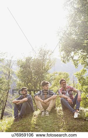 Three young men sitting on grass View Large Photo Image Stock Photograph - Three young men sitting on grass. Fotosearch
