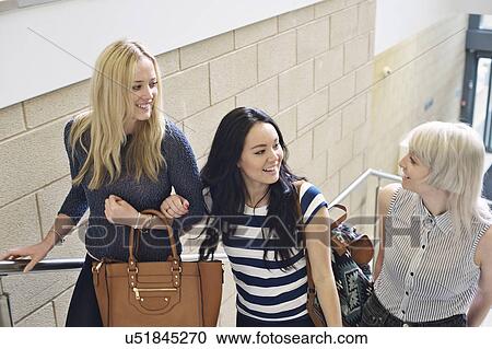 Stock Image - Three young women on staircase talking. Fotosearch