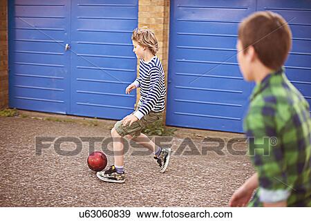 Two boys playing football by garage View Large Photo Image Stock Photo - Two boys playing football by garage. Fotosearch