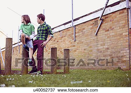 Two boys sitting on wooden poles View Large Photo Image Stock Photo - Two boys sitting on wooden poles. Fotosearch