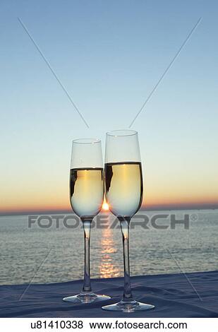 Stock Photo - Two champagne flutes against sunset. Fotosearch