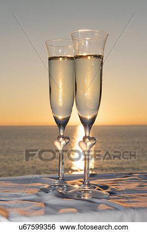 Stock Photograph - Two champagne flutes against sunset. Fotosearch