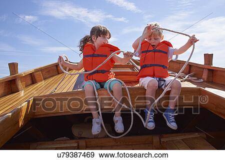 Two children sitting in boat, holding rope View Large Photo Image Stock Photo - Two children sitting in boat, holding rope. Fotosearch