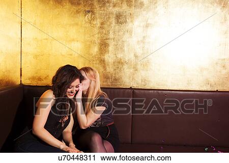 Two female friends whispering in nightclub View Large Photo Image Stock Image - Two female friends whispering in nightclub. Fotosearch