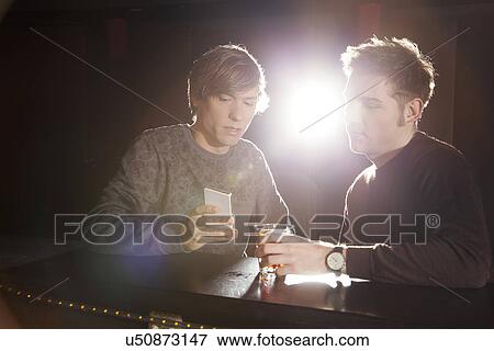 Two male friends looking at smartphone in nightclub View Large Photo Image Stock Photo - Two male friends looking at smartphone in nightclub. Fotosearch