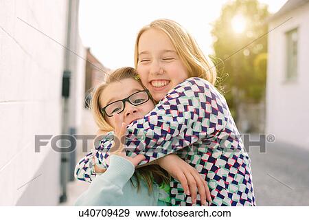 Two sisters hugging enthusiastically View Large Photo Image Stock Photo - Two sisters hugging enthusiastically. Fotosearch