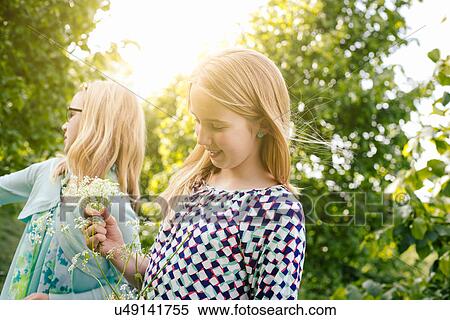 Stock Photography - Two sisters strolling with bunches of wildflowers. Fotosearch