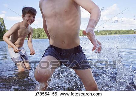 Stock Photography - Two young boys playing in lake. Fotosearch