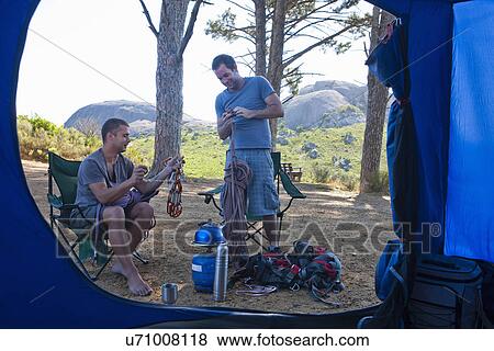 Two young men chatting and preparing camp View Large Photo Image Stock Photo - Two young men chatting and preparing camp. Fotosearch