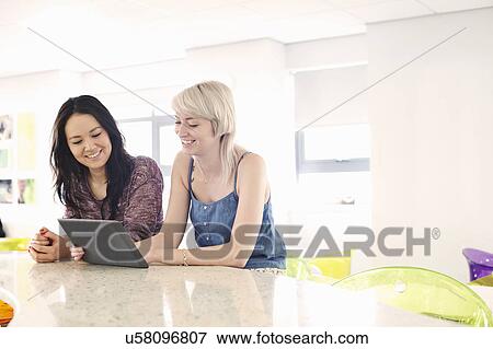 Two young women using digital tablet View Large Photo Image Stock Photo - Two young women using digital tablet. Fotosearch