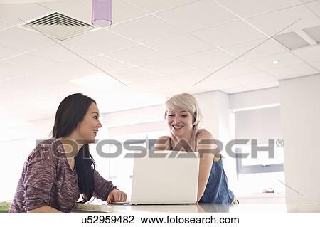 Stock Image - Two young women using laptop. Fotosearch