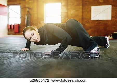 Stock Image - Woman doing stretching exercise in gym. Fotosearch