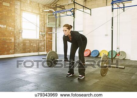 Stock Photo - Woman lifting barbell in gym. Fotosearch