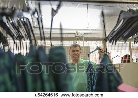 Stock Photograph - Worker hanging garments in clothing factory. Fotosearch