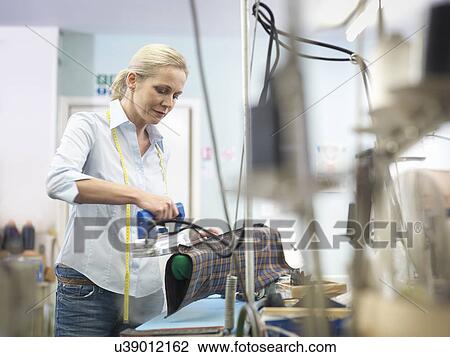 Worker ironing garment in clothing factory View Large Photo Image Stock Image - Worker ironing garment in clothing factory. Fotosearch