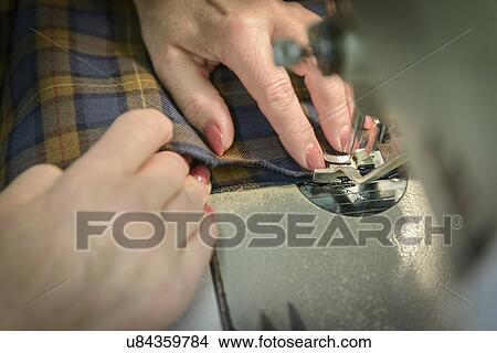 Picture - Worker sewing garment in clothing factory, close up. Fotosearch