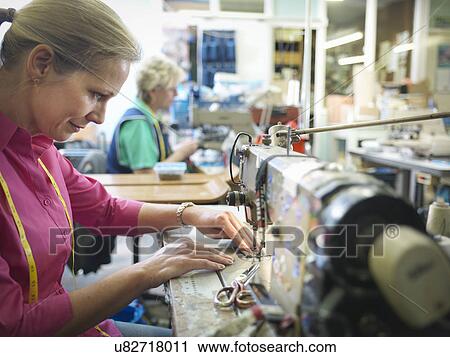 Stock Image - Worker sewing in clothing factory. Fotosearch