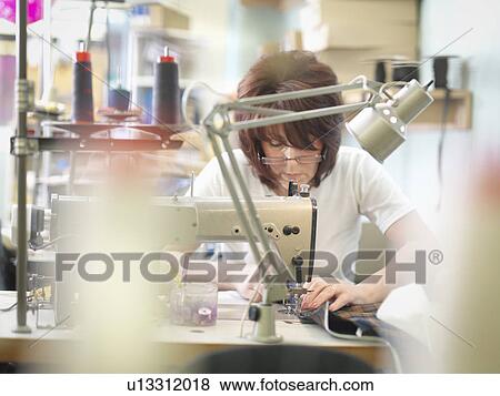 Stock Photo - Worker sewing in clothing factory. Fotosearch
