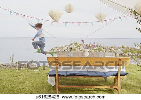 Young boy jumping mid air at party View Large Photo Image Stock Photograph - Young boy jumping mid air at party. Fotosearch