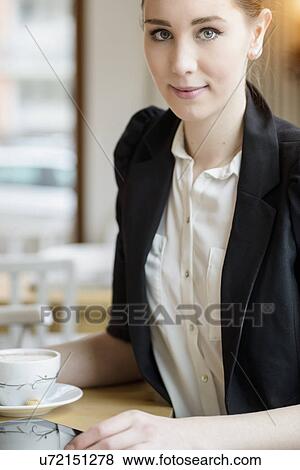Stock Photo - Young businesswoman in cafe having a coffee. Fotosearch