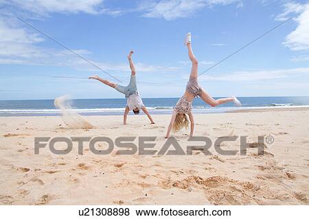 Stock Photo - Young couple doing handstands on beach. Fotosearch
