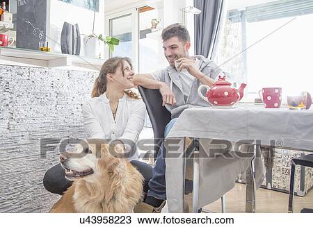 Stock Image - Young couple having breakfast, with dog. Fotosearch