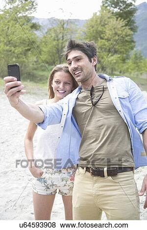 Young couple taking self portrait on Toce riverbank, Piemonte, Italy View Large Photo Image Stock Photo - Young couple taking self portrait on Toce riverbank, Piemonte, Italy. Fotosearch